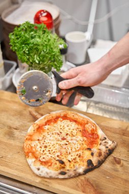 İtalyan mutfağı ve yemek pişirme konsepti. Napoli Pizzacısı 'nda pizza dilimleyen bir şef..