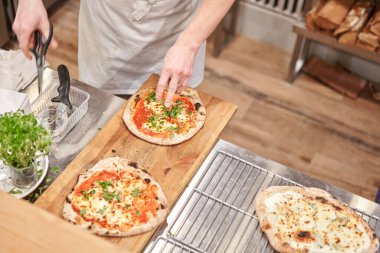 İtalyan mutfağı ve yemek pişirme konsepti. Napoli Pizzacısı 'nda pizza dilimleyen bir şef..