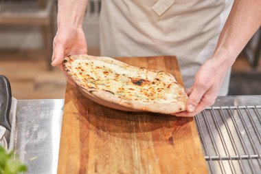 İtalyan mutfağı ve yemek pişirme konsepti. Napoli Pizzacısı 'nda pizza dilimleyen bir şef..