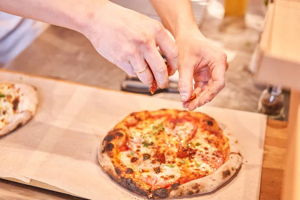 Chief fügt in der neapolitanischen Pizzeria Zutaten zur Pizza hinzu. Italienische Küche und Kochkonzept. — Stockfoto