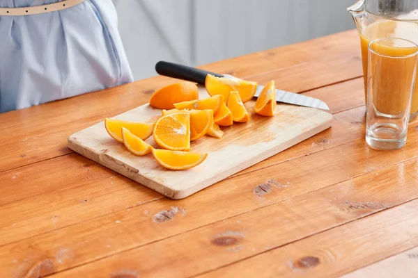 Closeup of a sliced orange. Healthy food, fresh fruit, juicy oranges. Mother and son are smiling while having a breakfast in kitchen. Bright morning in the kitchen. — Stock Photo, Image