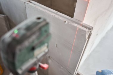 The construction worker Measures horizon level with a laser level. Construction of internal walls in the apartment using a plaster concrete plate with groove ridge. Gypsum plate clipart
