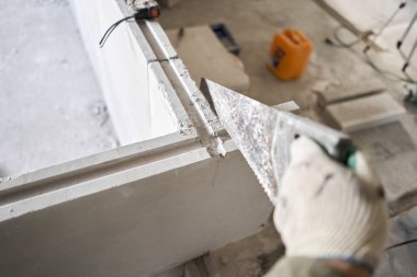 El testeresiyle alçıtaşı testeresi. Dairenin iç duvarlarının yapımında alçıdan betondan bir plaka ve yiv sırtı kullanılıyor. Bitirmeden yeni bina. dil ve yiv alçıtaşı blokları