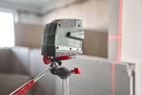 Працівник будівництва вимірює рівень горизонту з лазерним рівнем. Будівництво внутрішніх стін в квартирі з використанням гіпсової бетонної плити з канавками. Гіпсова плита — стокове фото