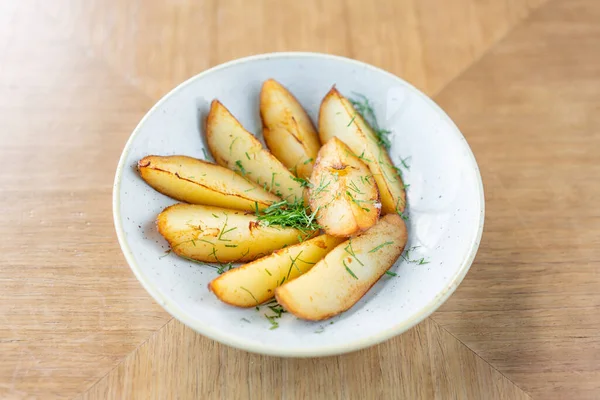 Roasted Potato country style with dill in white bowl on wooden background