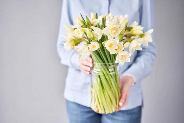 White narcissus. Spring Flowers in woman hands. Bouquet flowers in a vase.