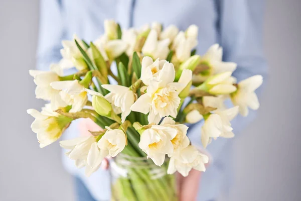 White narcissus. Spring Flowers in woman hands. Bouquet flowers in a vase.