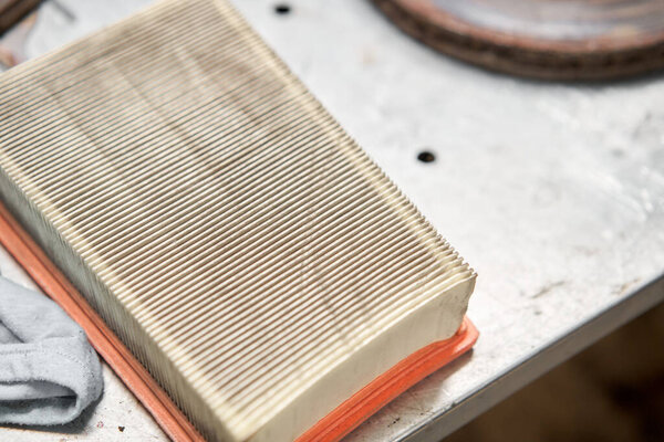 Old dirty automotive engine air filter on metal table of an auto mechanic. Auto repair concept.
