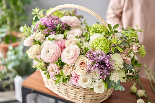 Έννοια ανθοπωλείου. Ανθοπωλείο γυναίκα δημιουργεί ρύθμιση λουλούδι σε ένα ψάθινο καλάθι. Όμορφο μπουκέτο από μικτά λουλούδια. Ωραία φρέσκια παρέα. Παράδοση λουλουδιών. — Φωτογραφία Αρχείου