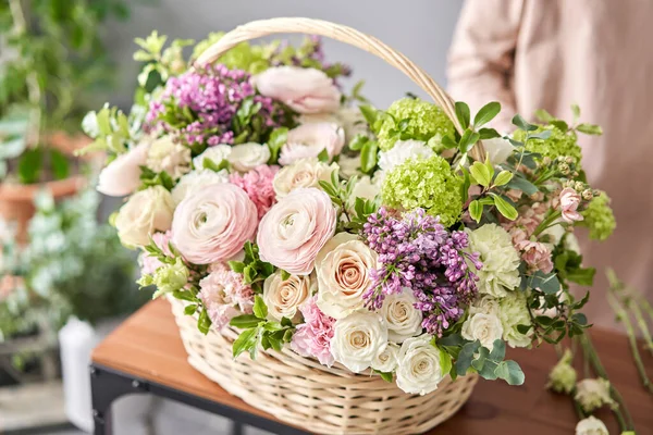 Concepto de tienda floral. Mujer florista crea arreglo floral en una canasta de mimbre. Hermoso ramo de flores mixtas. Hermoso grupo fresco. Entrega de flores . —  Fotos de Stock