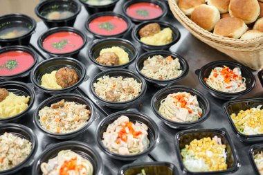 Bir sıra plastik tek kullanımlık beslenme çantası ve sağlıklı doğal yiyecekler. Çorbalar, kremalı çorba, garnitürlü ana yemek, salatalar. Yemek servisi. Ofiste öğle yemeği..