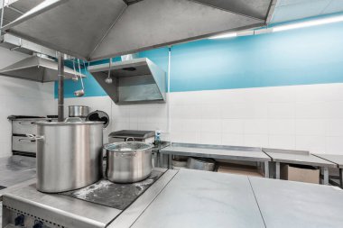 Profesyonel mutfakta yüzey ve mutfak ekipmanları var. Hazırlık masaları, tavalar, tencereler, ocaklar ile yemek pişirme.