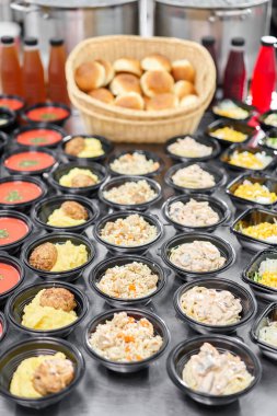 Bir sıra plastik tek kullanımlık beslenme çantası ve sağlıklı doğal yiyecekler. Çorbalar, kremalı çorba, garnitürlü ana yemek, salatalar. Yemek servisi. Ofiste öğle yemeği..