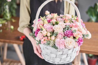 Küçük çiçekçi ve çiçek teslimatı. Wicker sepetinde çiçek aranjmanı. Kadın elinde güzel bir buket karışık çiçek. Yakışıklıymış..