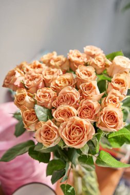 Çiçeklerin kahve rengi, okaliptüslü kapuçino gülleri. Cam vazoda küçük güzel buketler. Çiçek dükkanı konsepti. Çiçek teslimatı