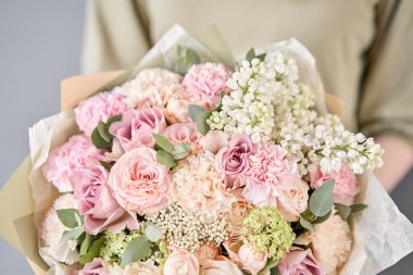 Küçük çiçekçi ve çiçek teslimatı. Kadın ellerinde güzel bir buket karışık çiçek. Çiçekçide çiçekçinin işi. Taze kesilmiş çiçek getirdim..