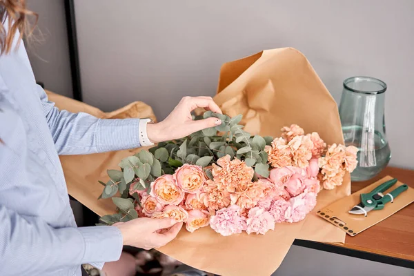 Mujer descomprimir conjunto de flores en la mesa de madera. Flores recién cortadas para la decoración del hogar. Entrega flor . — Foto de Stock