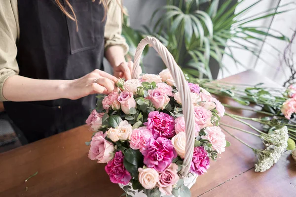 Conceito de loja floral. Mulher florista cria arranjo de flores em uma cesta de vime. Belo buquê de flores mistas. Bonito grupo fresco. Entrega de flores . — Fotografia de Stock