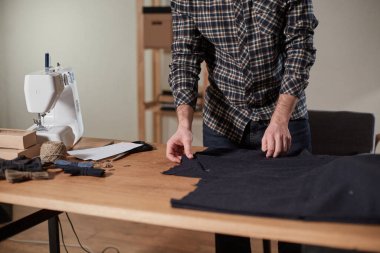 Terzi yün kesim kumaşı. Çizgi deseni. El sanatları ustası yün kumaştan papyonlar için dikdörtgen boşluklar yapıyor. Tekstil atölyesinde dikiş makinesiyle çalışıyorum..