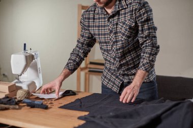 Terzi yün kesim kumaşı. Çizgi deseni. El sanatları ustası yün kumaştan papyonlar için dikdörtgen boşluklar yapıyor. Tekstil atölyesinde dikiş makinesiyle çalışıyorum..