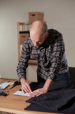 Terzi yün kesim kumaşı. Çizgi deseni. El sanatları ustası yün kumaştan papyonlar için dikdörtgen boşluklar yapıyor. Tekstil atölyesinde dikiş makinesiyle çalışıyorum..