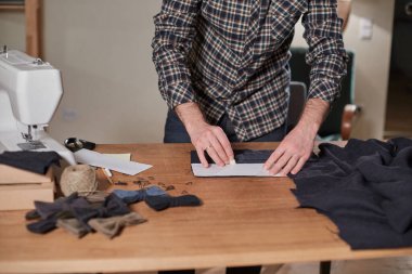 Terzi yün kesim kumaşı. Çizgi deseni. El sanatları ustası yün kumaştan papyonlar için dikdörtgen boşluklar yapıyor. Tekstil atölyesinde dikiş makinesiyle çalışıyorum..