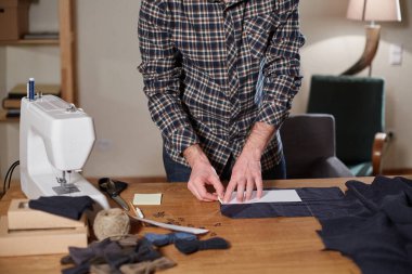 Terzi yün kesim kumaşı. Çizgi deseni. El sanatları ustası yün kumaştan papyonlar için dikdörtgen boşluklar yapıyor. Tekstil atölyesinde dikiş makinesiyle çalışıyorum..