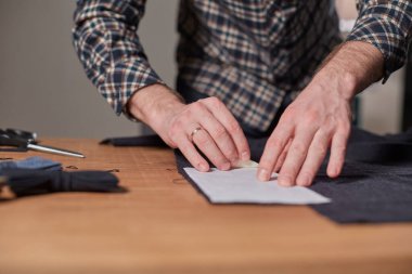 Terzi yün kesim kumaşı. Çizgi deseni. El sanatları ustası yün kumaştan papyonlar için dikdörtgen boşluklar yapıyor. Tekstil atölyesinde dikiş makinesiyle çalışıyorum..