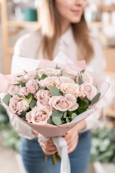 女人手里拿着一束美丽的紫红色玫瑰。花店花商的工作。送新鲜切花。欧洲花店. — 图库照片