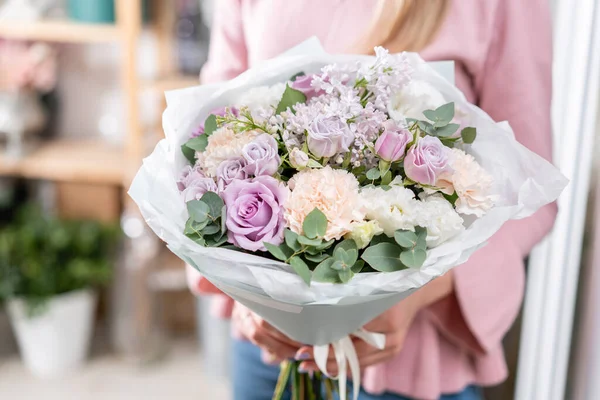 Hermoso ramo en manos de mujeres. el trabajo de la floristería en una florería. Entrega flor cortada fresca. Tienda floral europea . — Foto de Stock