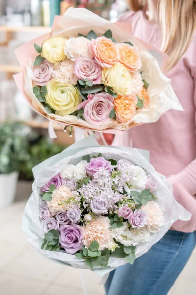 Dos hermosos ramos en manos de mujeres. el trabajo de la floristería en una florería. Entrega flor cortada fresca. Tienda floral europea . — Foto de Stock