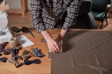 Terzi 'nin yakın çekimleri, yün kumaş kesimi. El sanatları ustası yün kumaştan papyonlar için dikdörtgen boşluklar yapıyor. Tekstil atölyesinde dikiş makinesiyle çalışıyorum..