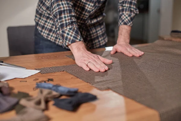Close-up handen van Tailor, knippen wollen stof. Vakman Maakt rechthoekige losse flodders voor strikjes van wollen stof. Werken met naaimachine in een textielatelier. — Stockfoto