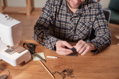 Terzi yün kumaştan papyon yapar. Tekstil atölyesinde dikiş makinesiyle çalışıyorum..