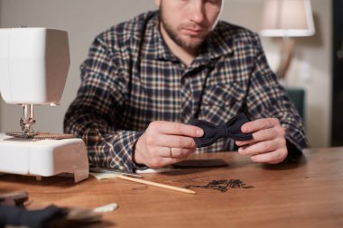 Terzi yün kumaştan papyon yapar. Tekstil atölyesinde dikiş makinesiyle çalışıyorum..