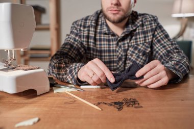 Terzi yün kumaştan papyon yapar. Tekstil atölyesinde dikiş makinesiyle çalışıyorum..