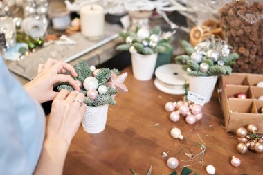 Bir kadın Noel düzenini süslüyor. Dekoratif süsler konusunda yüksek lisans. Noel dekorunu kendi elleriyle yaptılar. Yeni yıl kutlaması. Çiçekçi