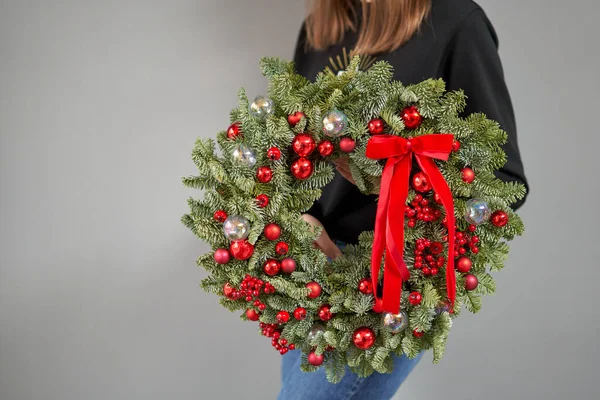 Kerststemming. Prachtige feestelijke krans van verse sparren in vrouwenhanden. Kerstboom. Bokeh van Garland lichten op de achtergrond. — Stockfoto