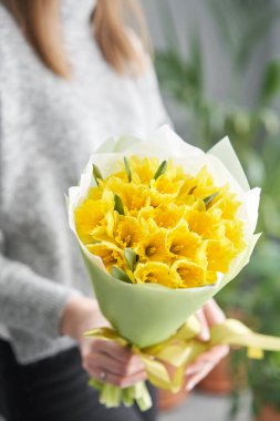 Narcissus. Kadınların elinde sarı renkli çiçeklerden bir buket. Çiçekçi dükkanındaki çiçekçinin işi..