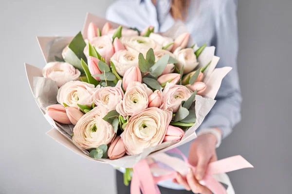 Бледно-розовые тюльпаны и цветки ранункула с зеленым эвкалиптом. Работа флориста в цветочном магазине . — стоковое фото