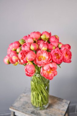 Ahşap masadaki cam vazoda mercan şakayıklar. Katalog ya da internet mağazası için güzel şakayık çiçekleri. Çiçek dükkanı konsepti. Taze kesilmiş güzel bir buket. Çiçek teslimatı.