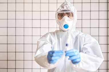 Doktor, 2019 nCoV analizi için tüp bezi tutuyor. Coronavirus testi. Mavi tıbbi eldiven ve kovid 19 virüsüne karşı korunmak için koruyucu yüz maskesi. Koronavirüs ve pandemik.