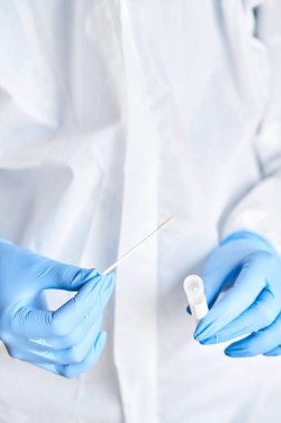 Doktor, 2019 nCoV analizi için tüp bezi tutuyor. Coronavirus testi. Mavi tıbbi eldiven ve kovid 19 virüsüne karşı korunmak için koruyucu yüz maskesi. Koronavirüs ve pandemik.