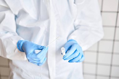 Doktor, 2019 nCoV analizi için tüp bezi tutuyor. Coronavirus testi. Mavi tıbbi eldiven ve kovid 19 virüsüne karşı korunmak için koruyucu yüz maskesi. Koronavirüs ve pandemik.