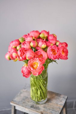 Ahşap masadaki cam vazoda mercan şakayıklar. Katalog ya da internet mağazası için güzel şakayık çiçekleri. Çiçek dükkanı konsepti. Taze kesilmiş güzel bir buket. Çiçek teslimatı.