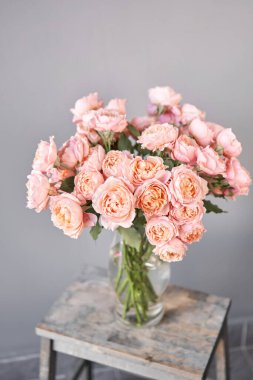 Çiçekçinin teslimat konsepti. Çok renkli güller, pastel pembe ve soluk turuncu renkler. Bir sürü tomurcuk. Çiçek doğal arka plan