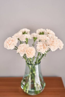 Tahta bir masadaki vazoda duran karanfil çiçekleri. Bir buket pembe çiçek. Evin dekorasyonu. Duvar kağıdı ve arkaplan.