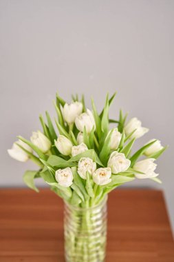 Cam vazoda beyaz renkli laleler. Çiçeklerin doğal arkaplanı. Diğerlerinin aksine sıra dışı çiçekler..