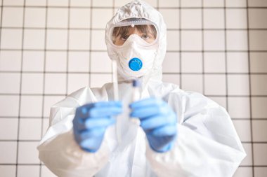 Doktor, 2019 nCoV analizi için tüp bezi tutuyor. Coronavirus testi. Mavi tıbbi eldiven ve kovid 19 virüsüne karşı korunmak için koruyucu yüz maskesi. Koronavirüs ve pandemik.