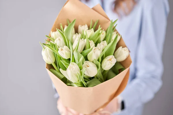 Beau bouquet de printemps de fleurs de tulipes blanches à la main de la femme. le travail du fleuriste dans un magasin de fleurs — Photo